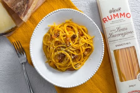 Piatto degli spaghetti alla carbonara con vicino un pacchetto di spaghetti Rummo